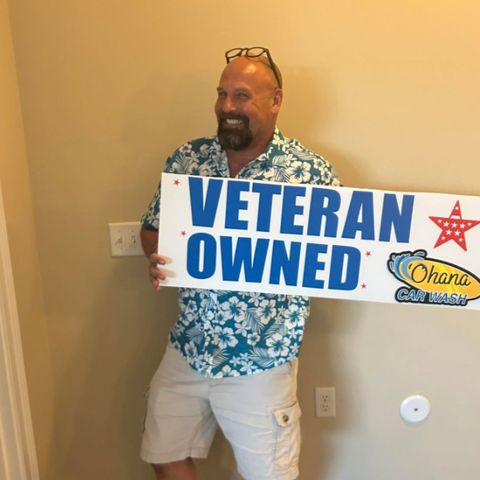 Nick, owner of Ohana Car Wash, holding a Veteran Owned sign